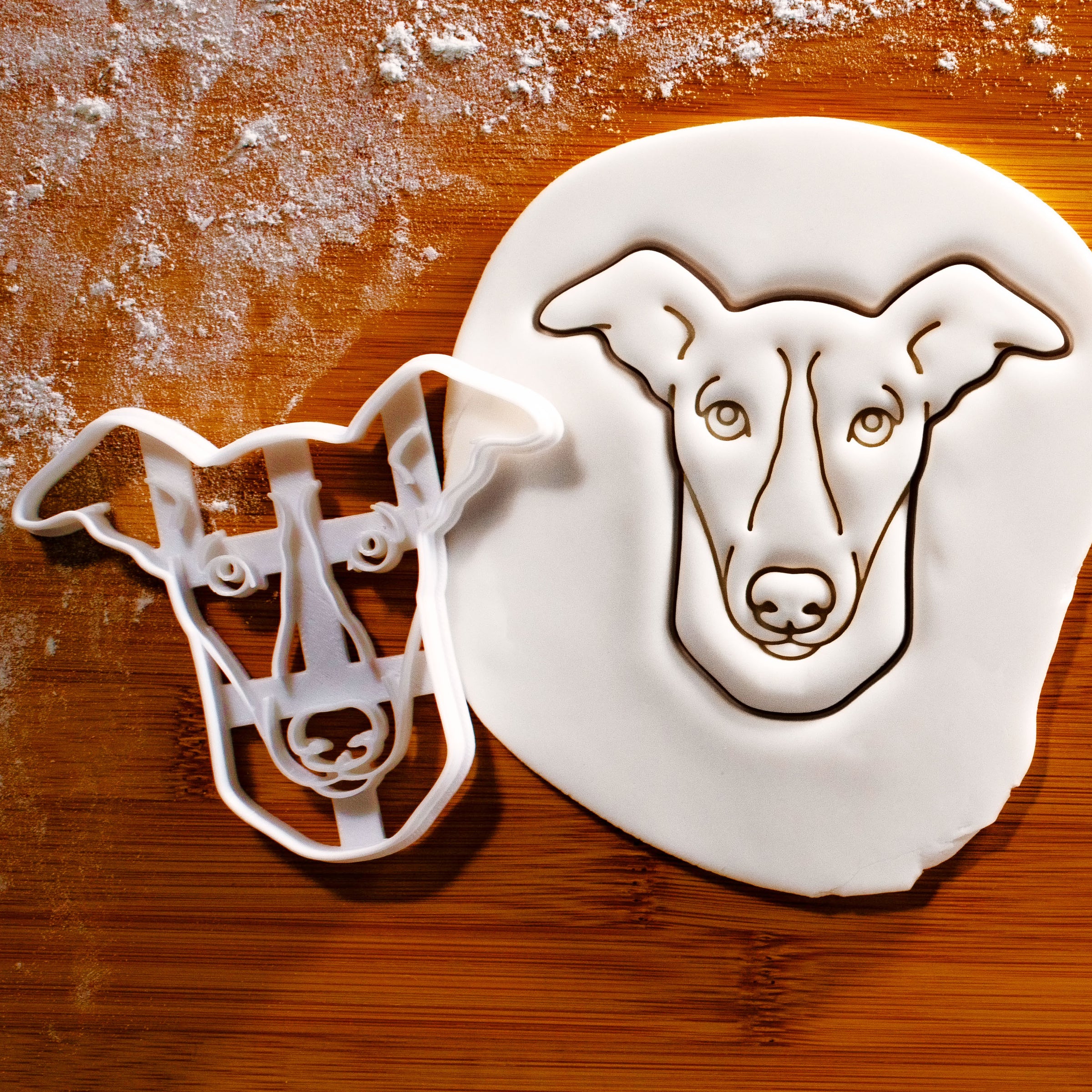 Whippet dog face cookie cutter pressed onto white fondant icing to show imprints - Bakerlogy