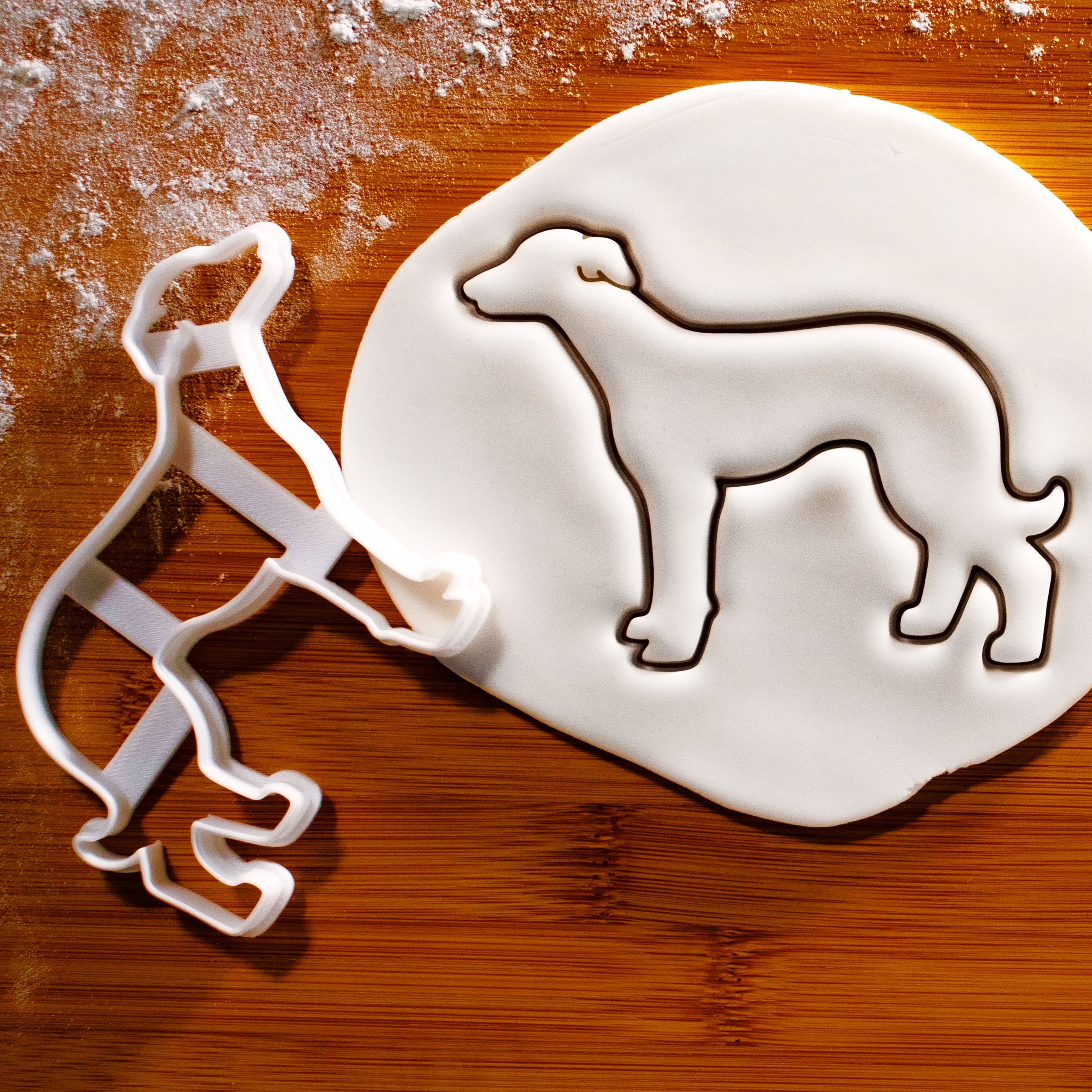 Whippet dog silhouette cookie cutter pressed onto white fondant icing to show imprints - Bakerlogy