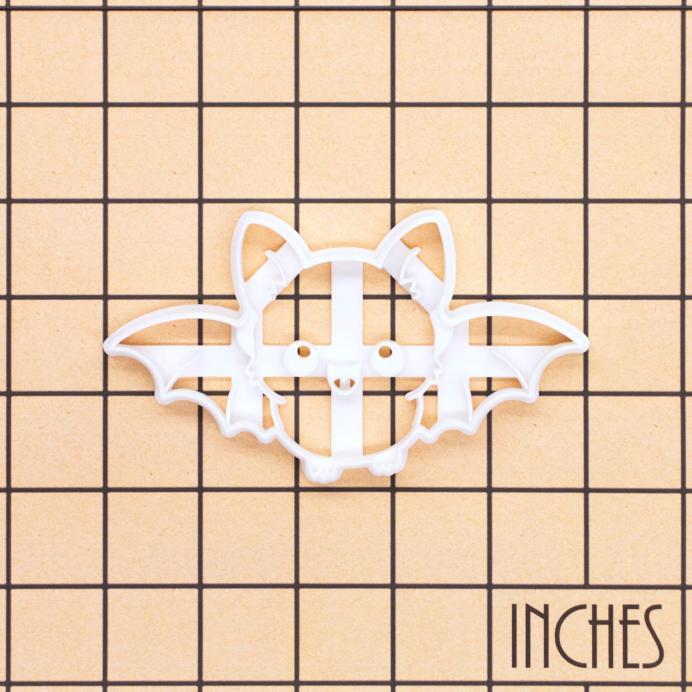 Flying Chibi Bat Cookie Cutter shown on an inch measurement grid for size reference