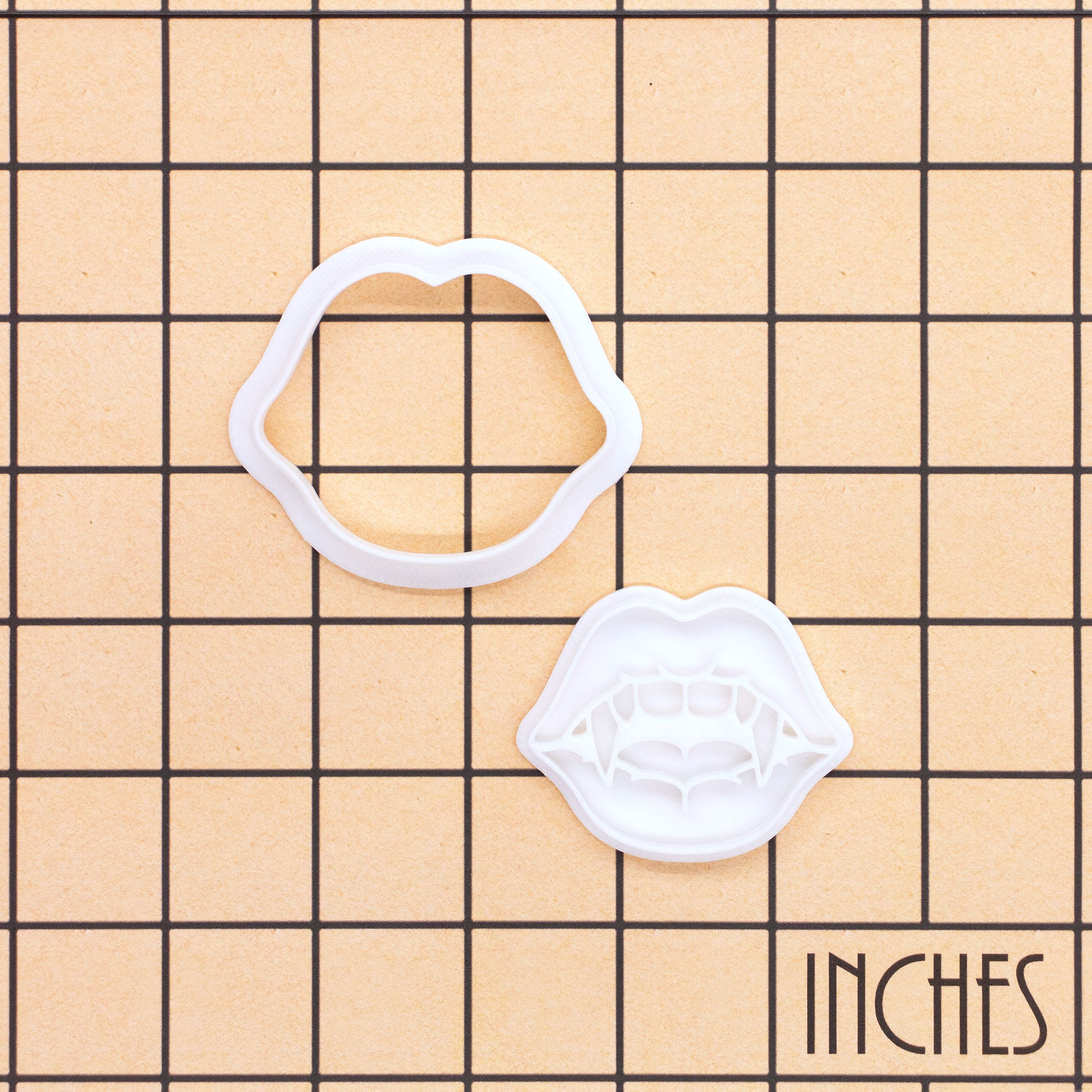 Vampire Fang Kiss Mini Cookie Cutter and separate stamp shown on an inch grid for size reference