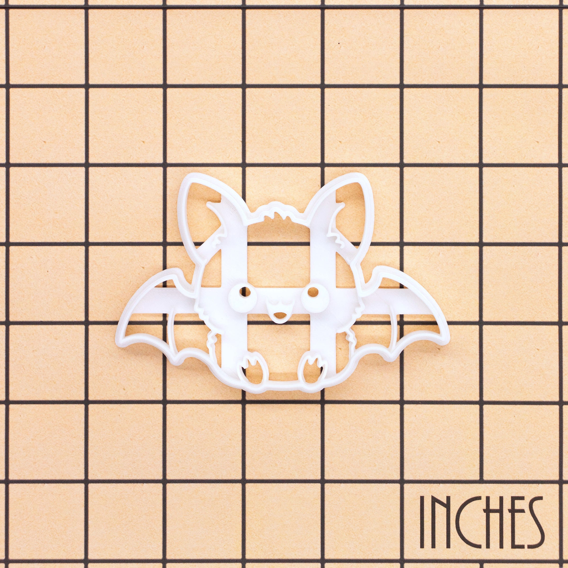 Sitting chibi bat Halloween cookie cutter shown on an inch grid for size reference