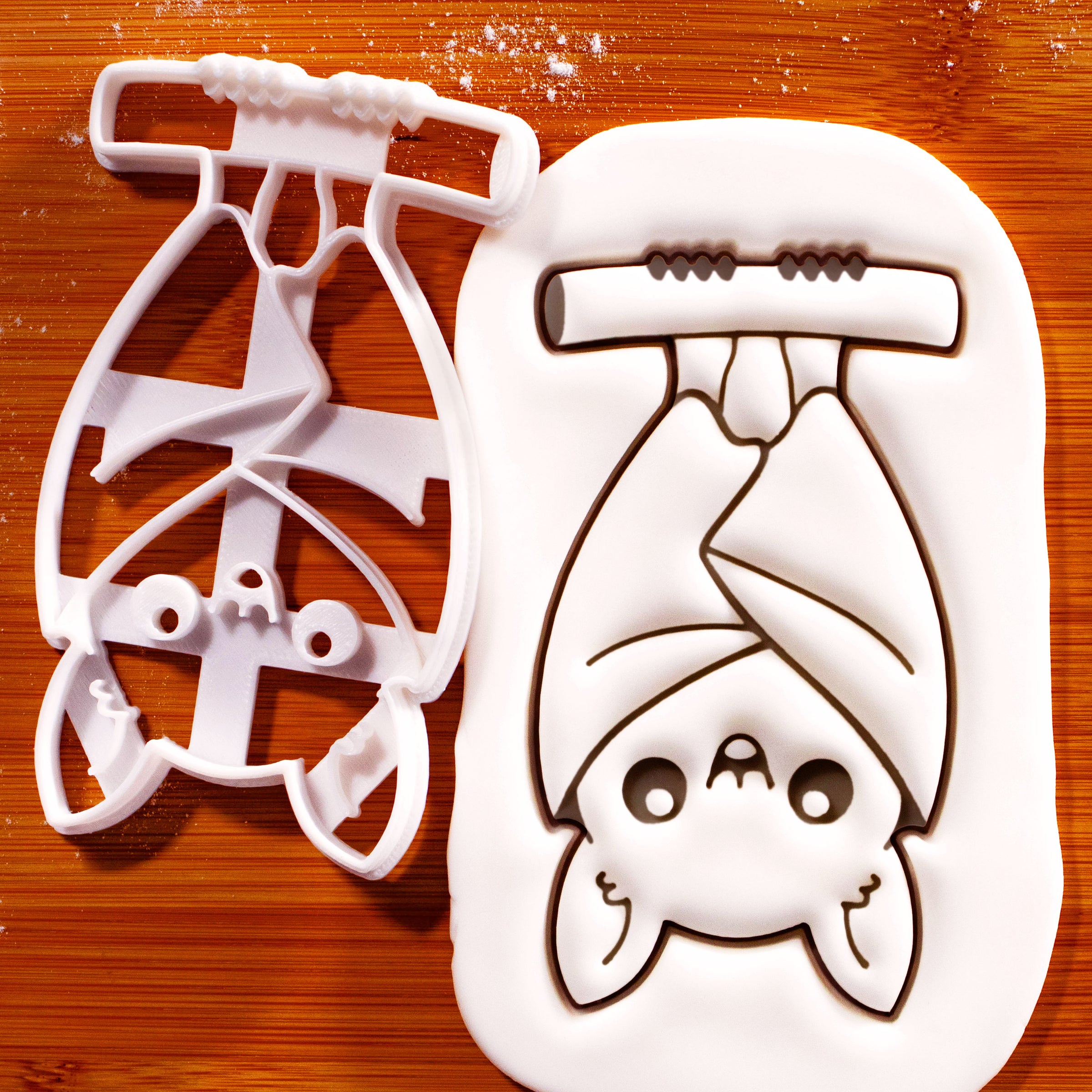 Hanging chibi bat cookie cutter creating an upside-down bat with folded wings for Halloween baking
