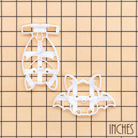 Sitting and hanging chibi bat Halloween cookie cutters shown on an inch measurement grid for size reference