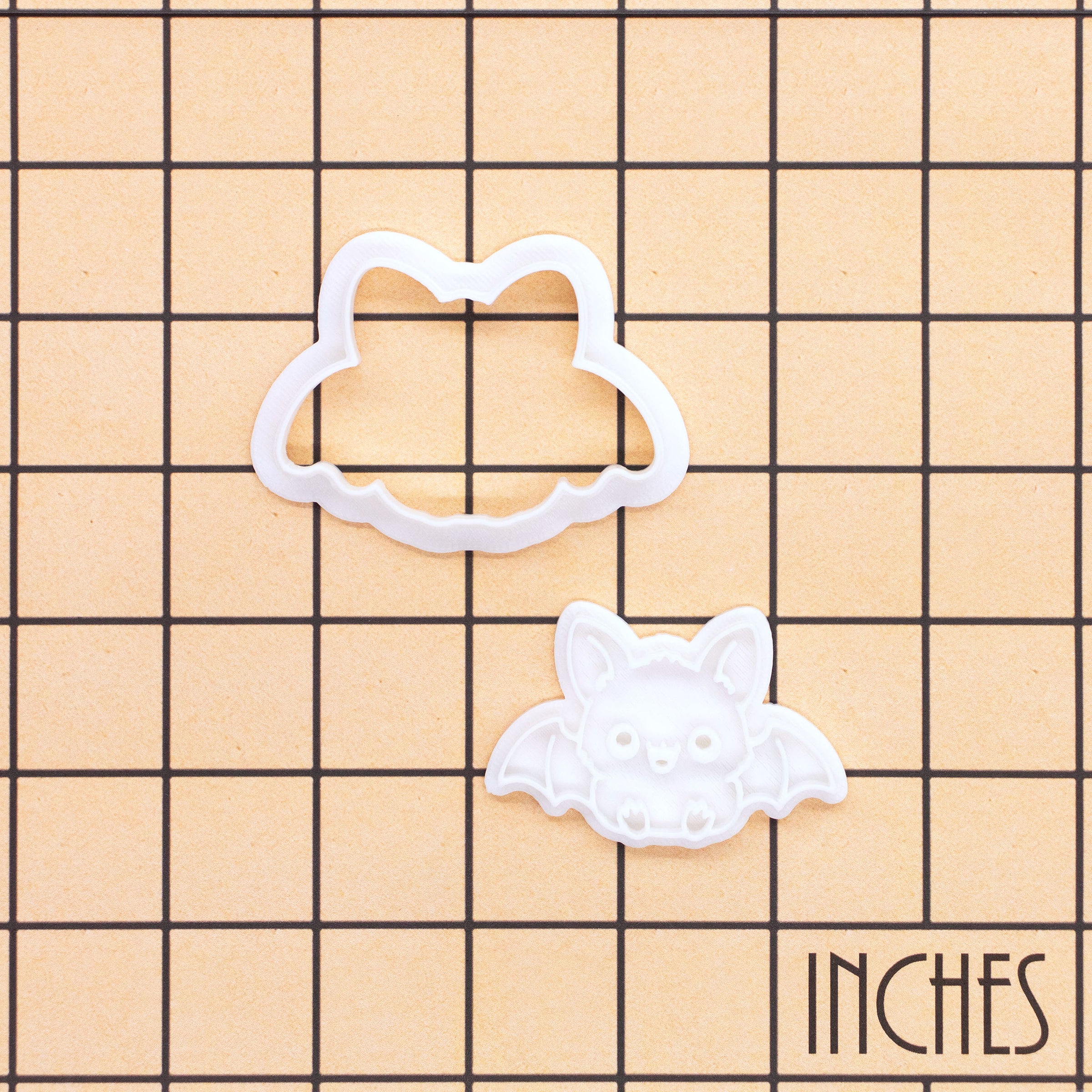 Sitting chibi bat mini cookie cutter and stamp shown on an inch measurement grid for size reference