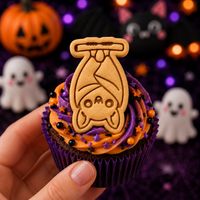 Hanging chibi bat embossed cookie used as a Halloween cupcake topper with orange and purple icing