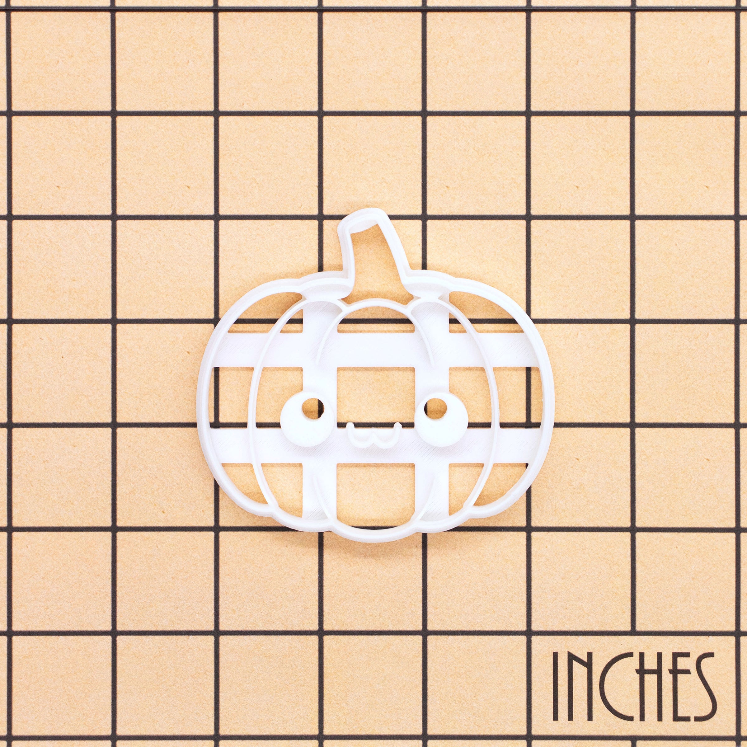 Kawaii pumpkin cookie cutter shown on an inch measurement grid