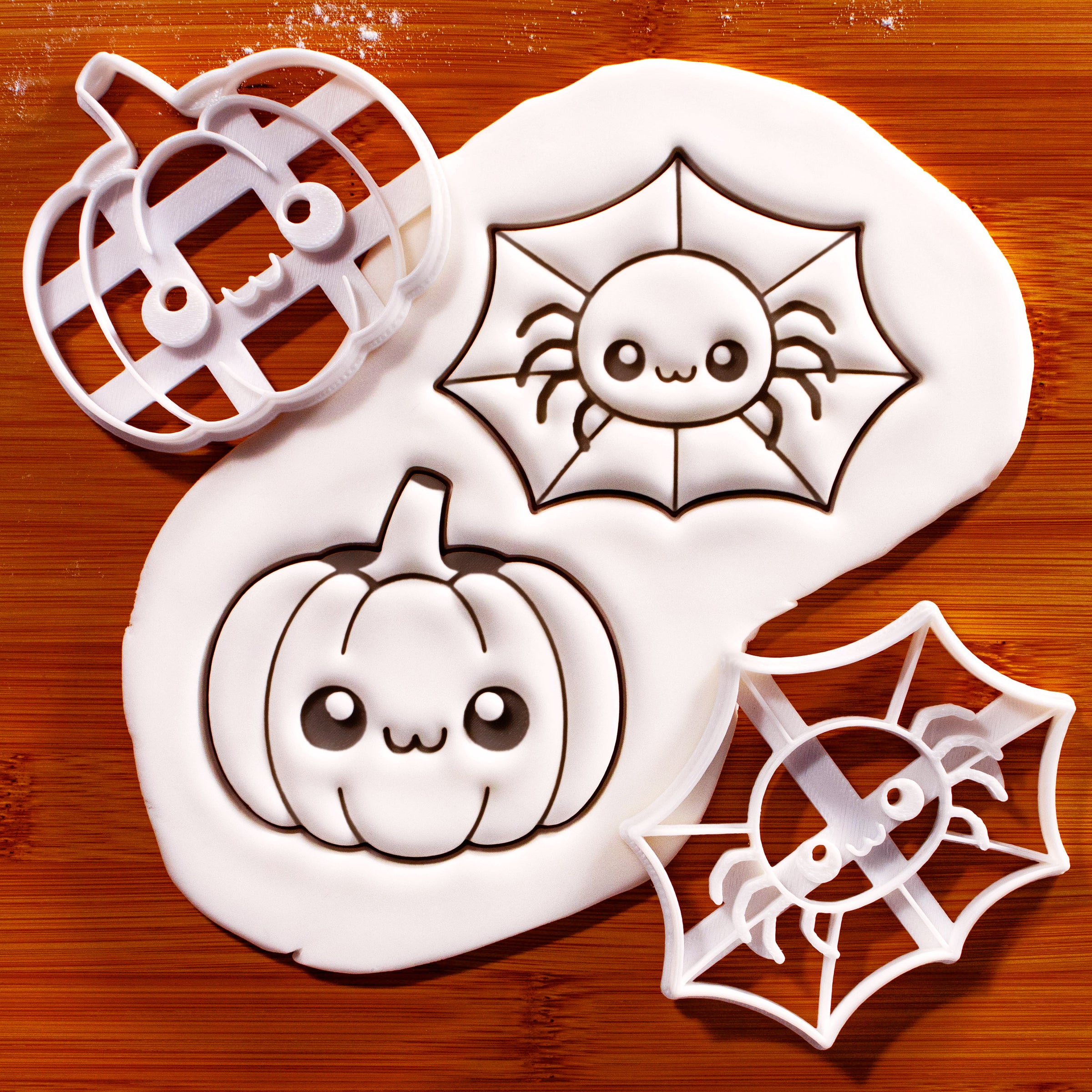 Chibi spider web and kawaii pumpkin cookie cutters beside detailed fondant impressions