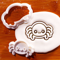 Chibi spider mini cookie cutter and matching stamp beside a fondant impression