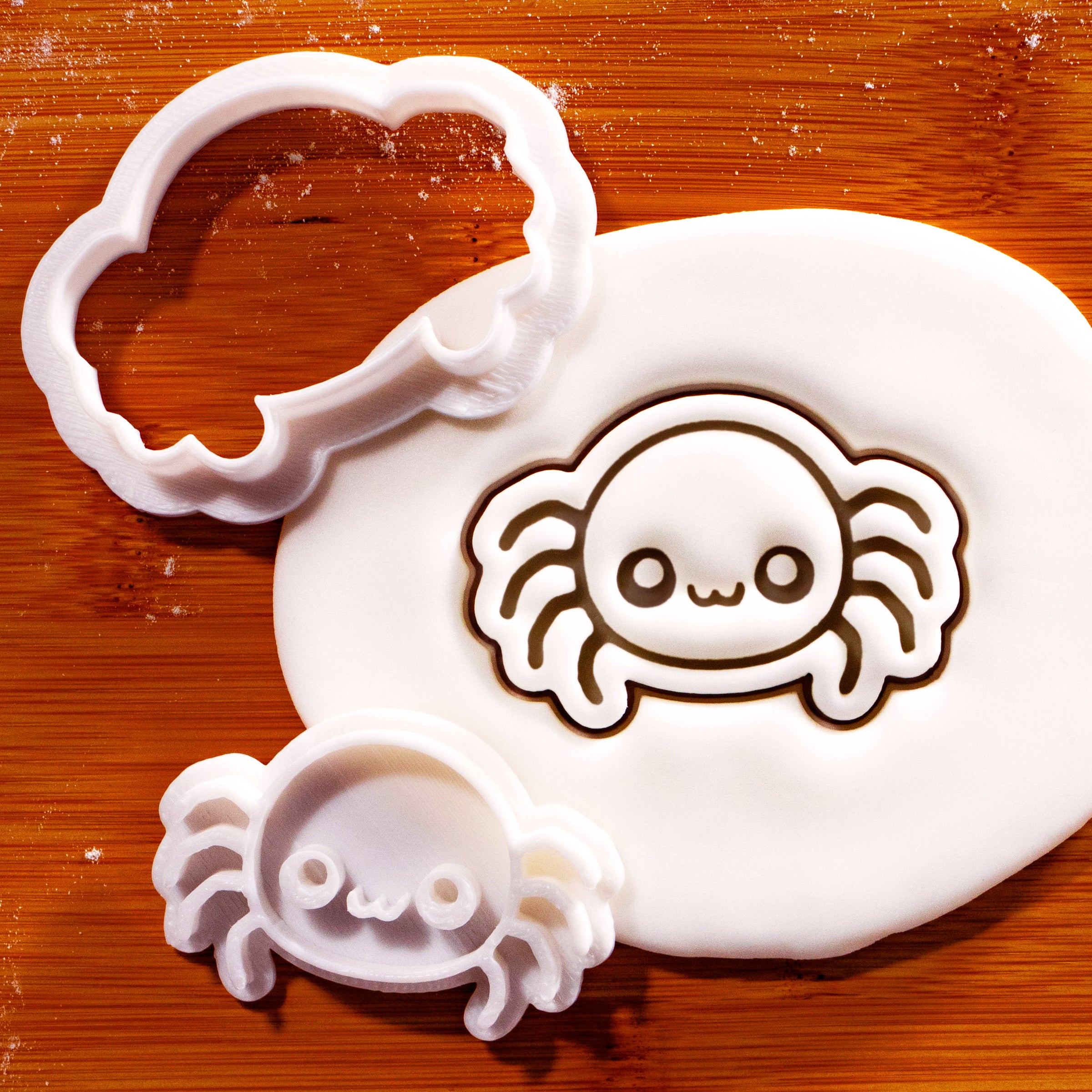 Chibi spider mini cookie cutter and matching stamp beside a fondant impression
