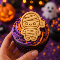 Chibi mummy stamped cookie used as a Halloween cupcake topper with orange and purple frosting