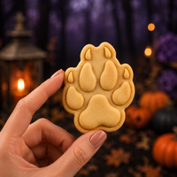 Wolf paw print mini cookie held by hand with detailed pads and claw marks