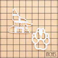 Set of two howling wolf and wolf paw print cookie cutters on inch grid