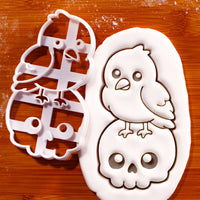 Kawaii raven on skull cookie cutter beside detailed stamped fondant impression
