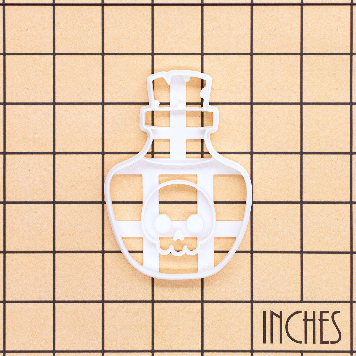 Kawaii poison potion skull bottle cookie cutter shown on an inch measurement grid