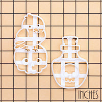 Raven on skull and poison potion cookie cutters shown on an inch measurement grid