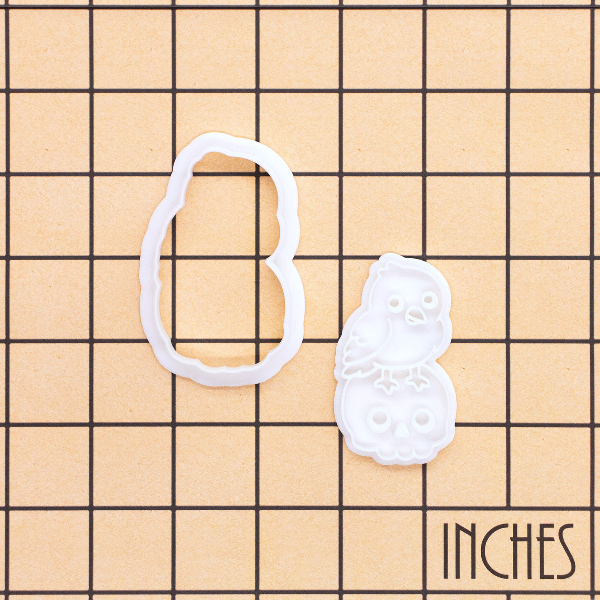 Kawaii raven on skull mini cookie cutter and stamp shown on an inch measurement grid