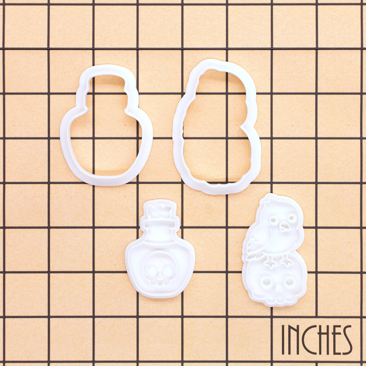 Raven on skull and poison potion mini cookie cutters and stamps shown on an inch measurement grid