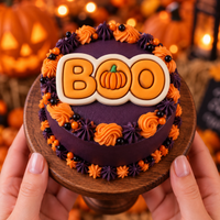 BOO pumpkin fondant cake topper on a purple and orange Halloween cake