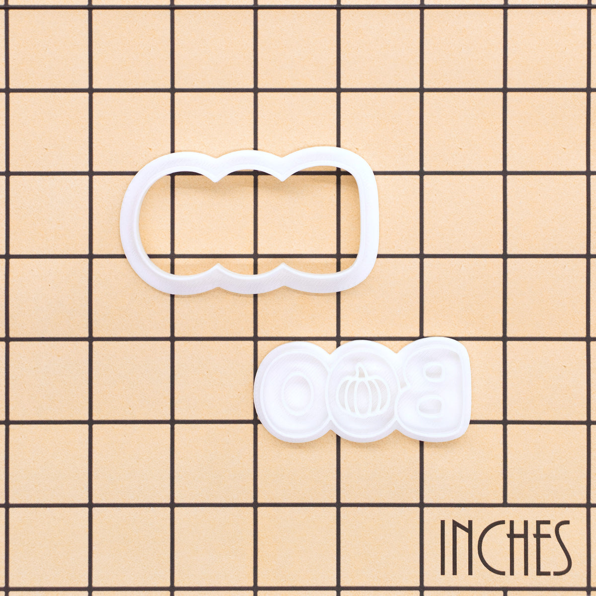 BOO pumpkin mini cookie cutter and stamp set shown on an inch measurement grid
