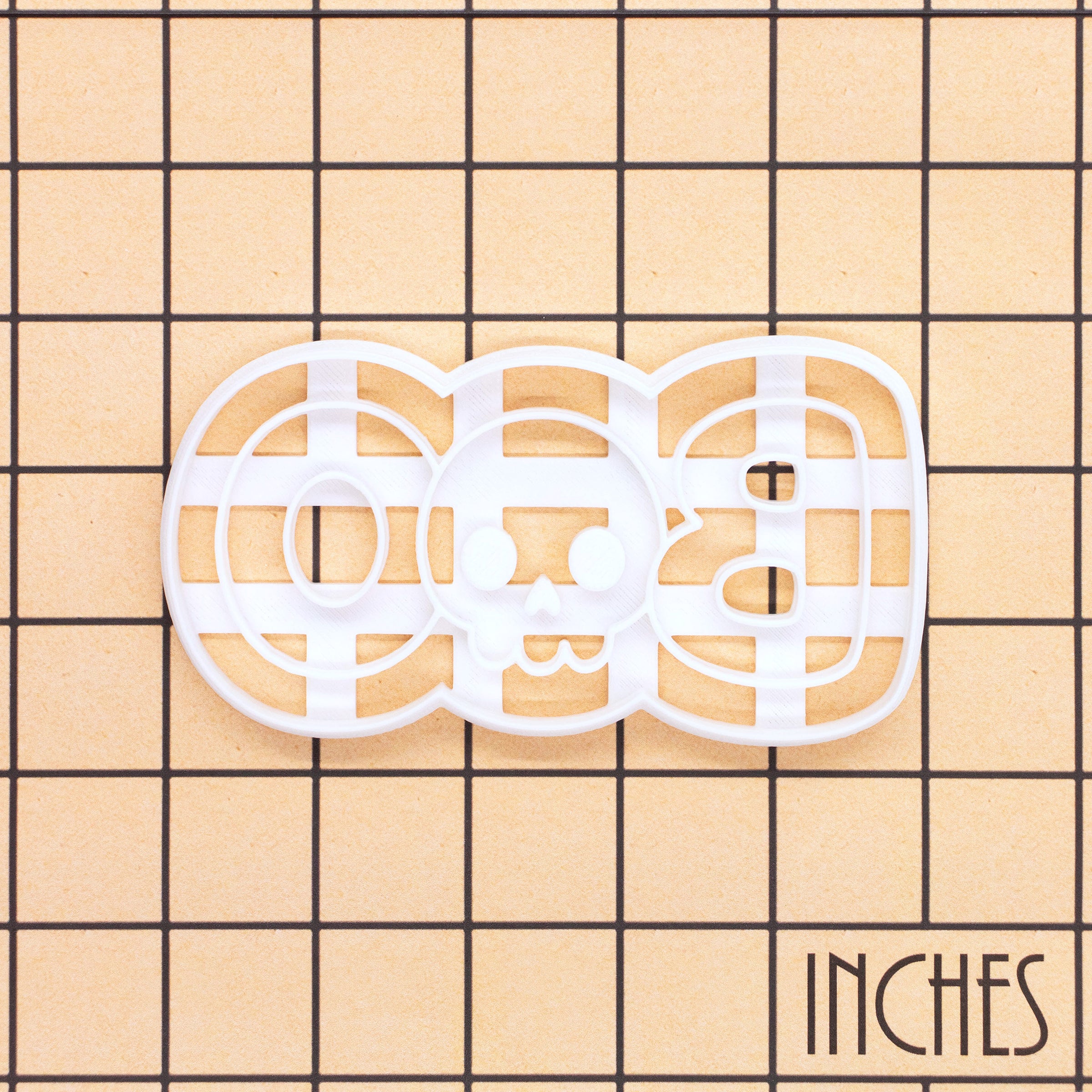 BOO skull Halloween cookie cutter shown on an inch measurement grid