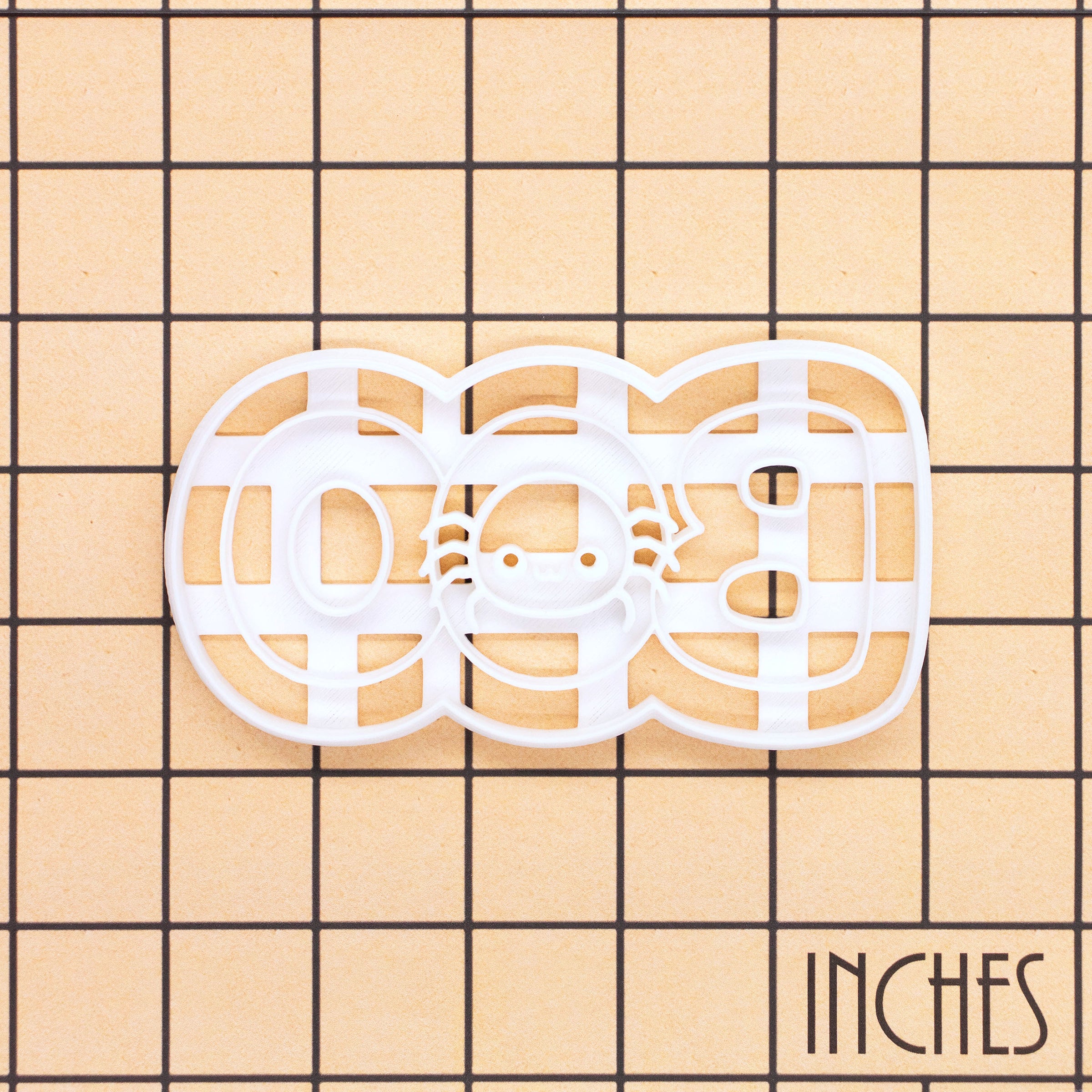 BOO spider Halloween cookie cutter shown on inch measurement grid for size reference