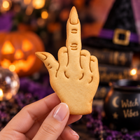 Witchy middle finger shaped cookie with pointed nails and embossed hand details held against a Halloween background