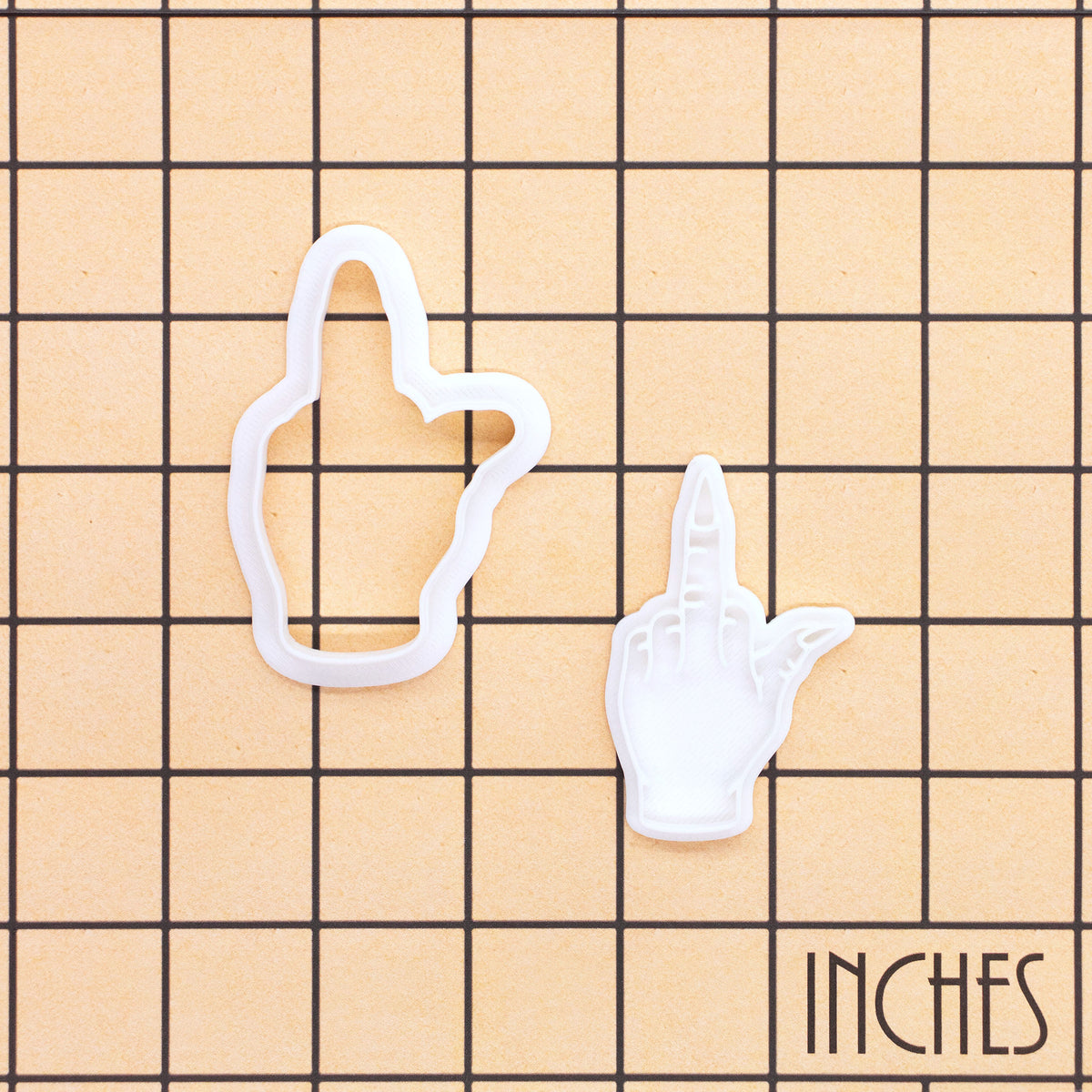 Witchy middle finger mini cookie cutter and matching stamp shown on an inch measurement grid