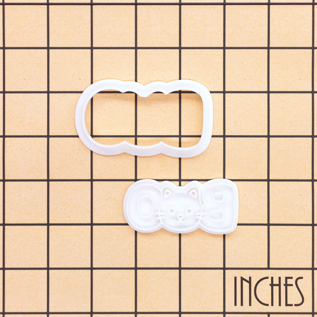 BOO cat face mini cookie cutter and stamp shown on inch measurement grid for size reference