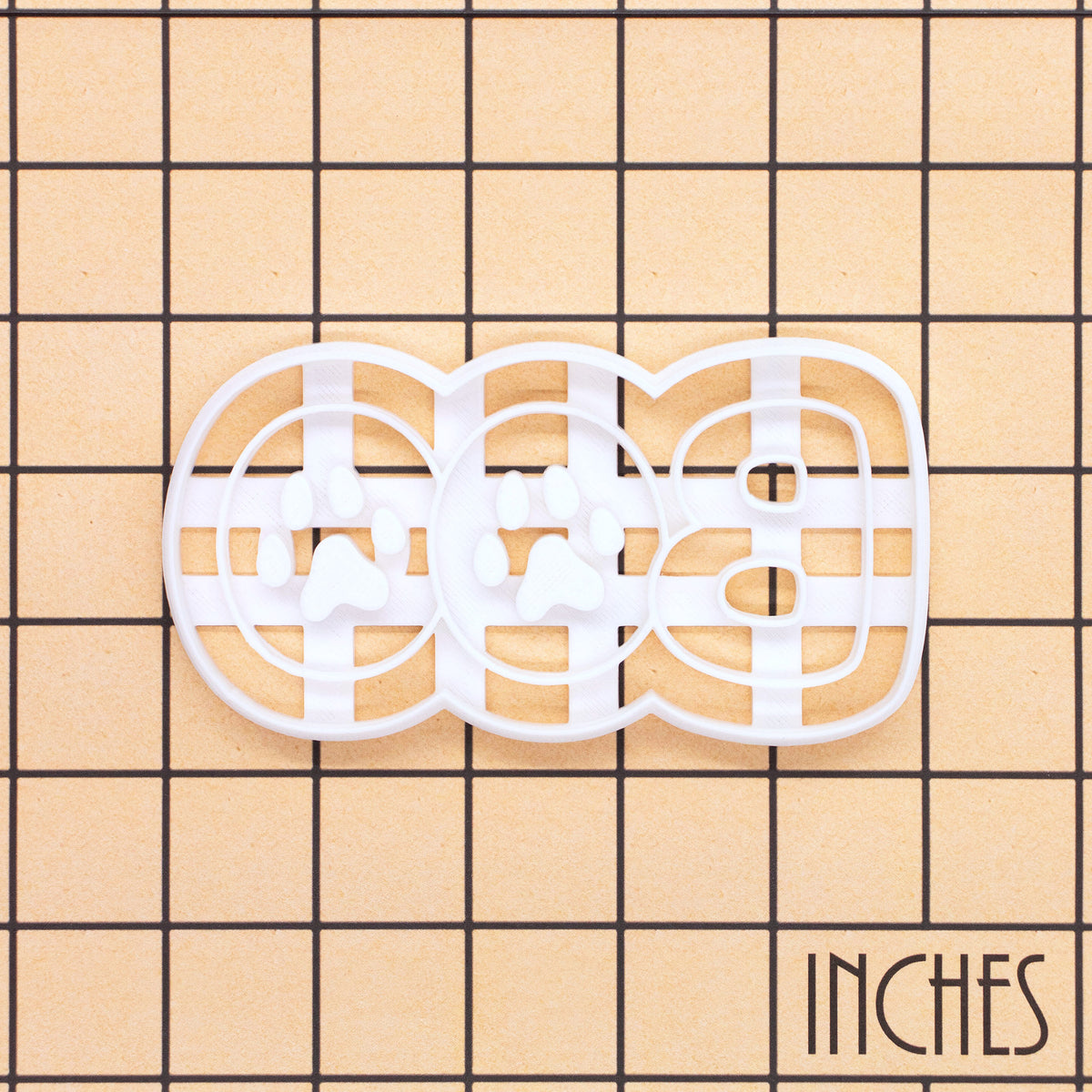 White BOO Paw Print Cookie Cutter with paw pad impression details shown on an inch measurement grid