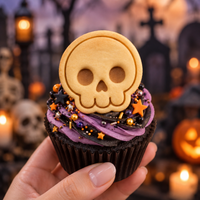 Mini side-view skull cookie topper on orange and purple Halloween cupcake