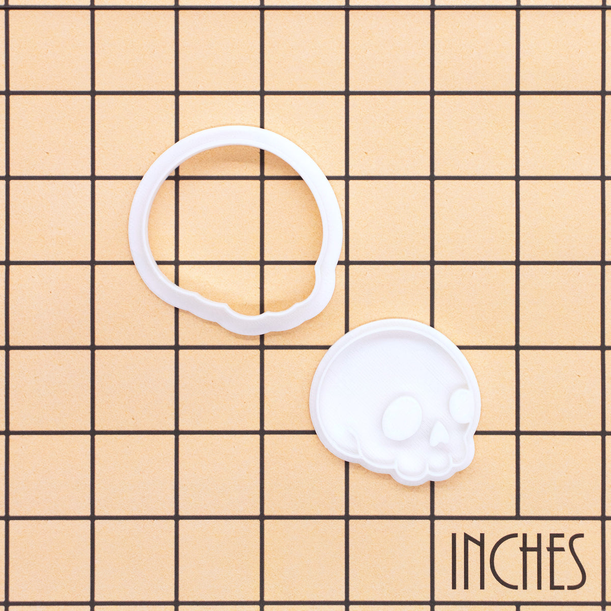 BAKERLOGY mini side-view skull cookie cutter and stamp set shown on inch grid