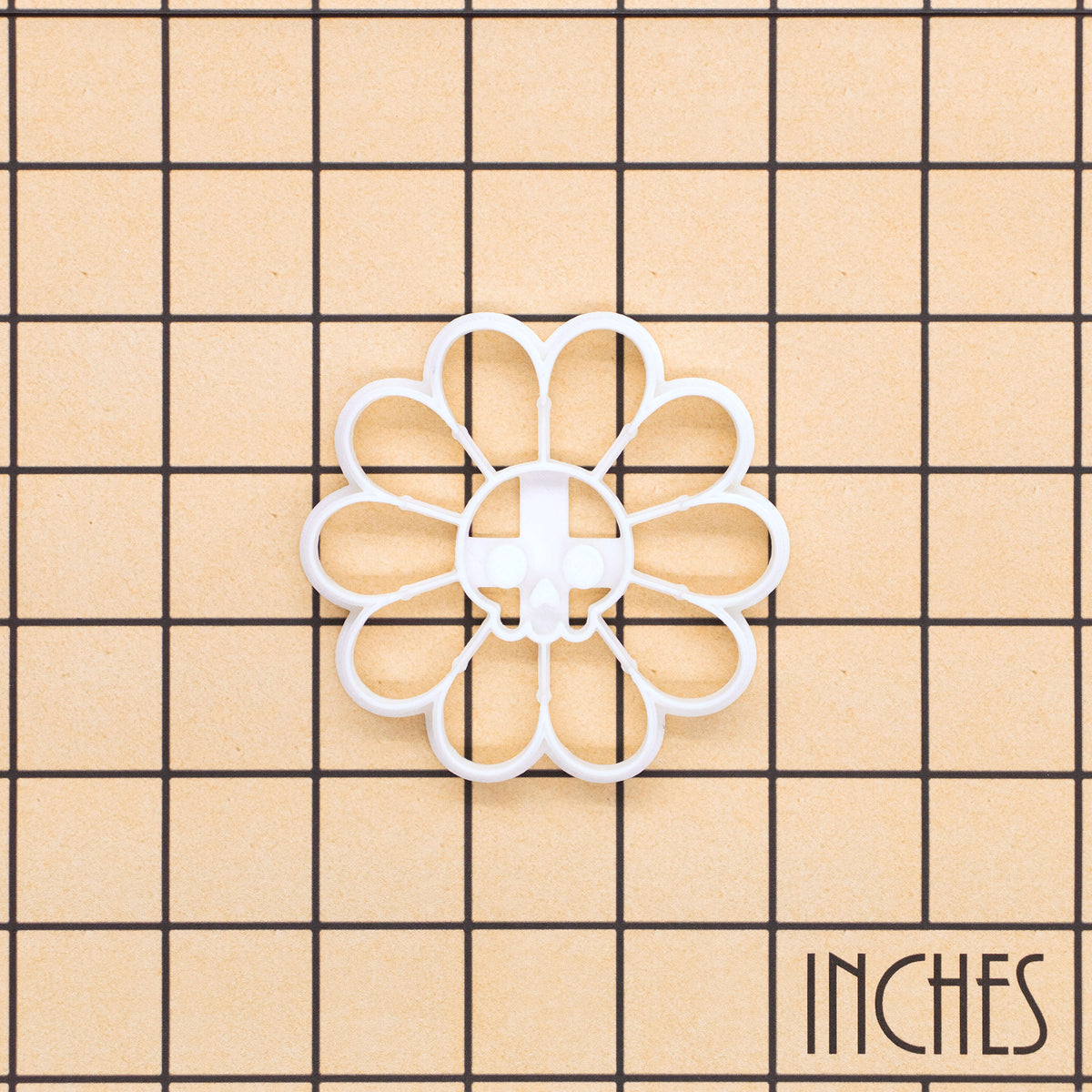 White Daisy Skull cookie cutter on inch grid showing gothic floral skull design