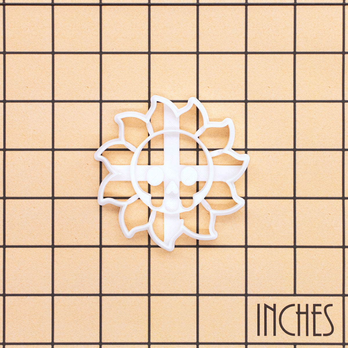 White Skull Sun cookie cutter on inch grid showing gothic celestial skull design