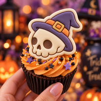 Coloured skull with witch hat fondant topper on orange frosted Halloween cupcake