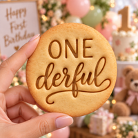 ONEderful cookie held in hand with first birthday party background