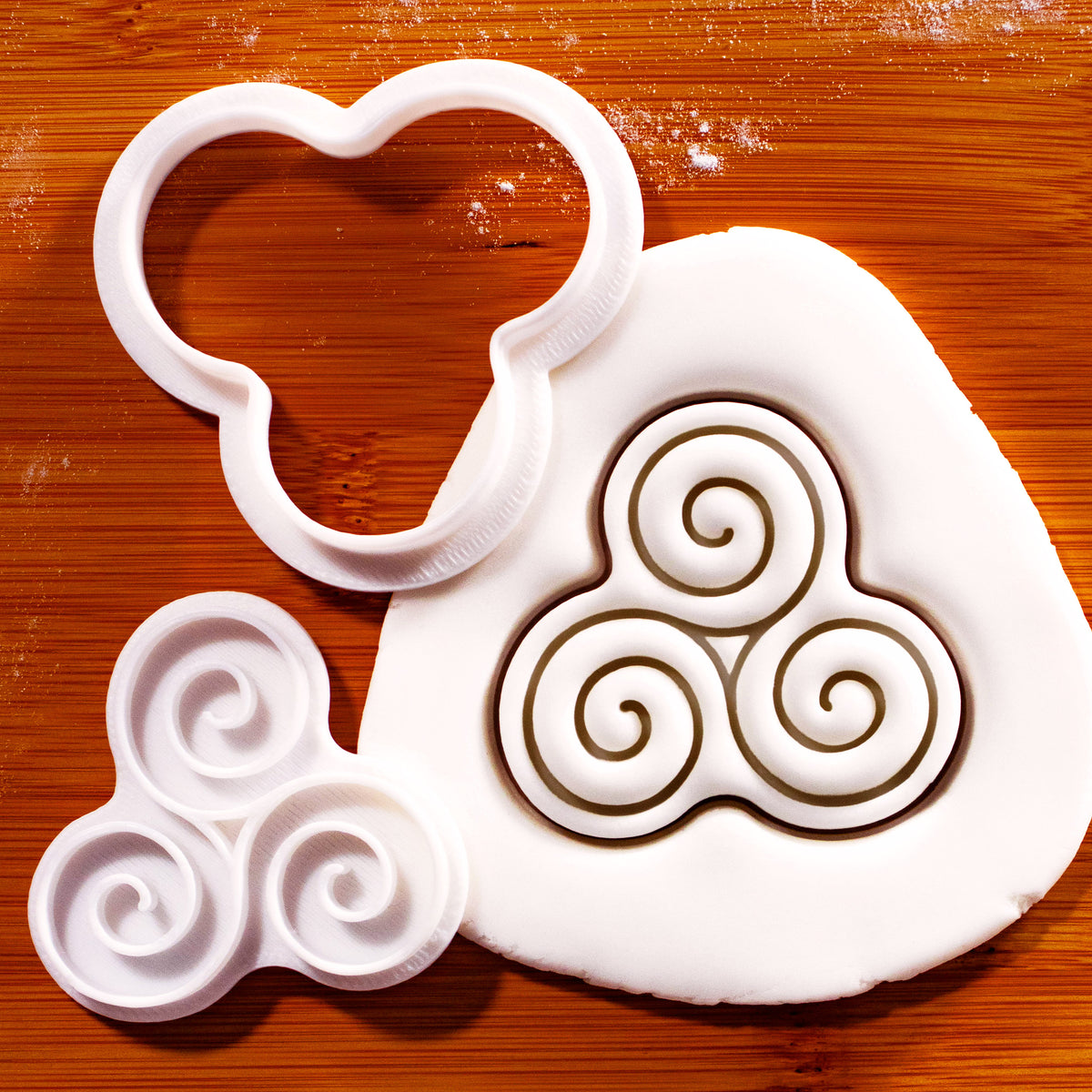 Triskelion mini cookie cutter and impression stamp creating Celtic triple spiral design in rolled fondant