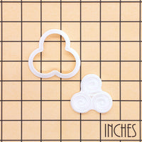 Triskelion mini cookie cutter and stamp set displayed on inch grid showing Celtic triple spiral design size