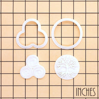 Tree of Life and Triskelion mini cookie cutter and stamp pieces displayed on inch measurement grid
