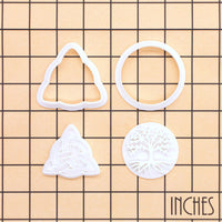Tree of Life and Triquetra mini cookie cutter and stamp pieces displayed on inch measurement grid