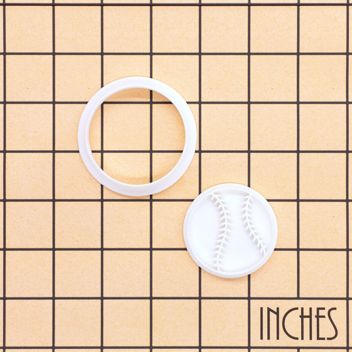 Softball mini cookie cutter and stamp set shown on inch measurement grid