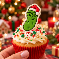Green Christmas pickle fondant topper with Santa hat and glasses on festive Christmas cupcake