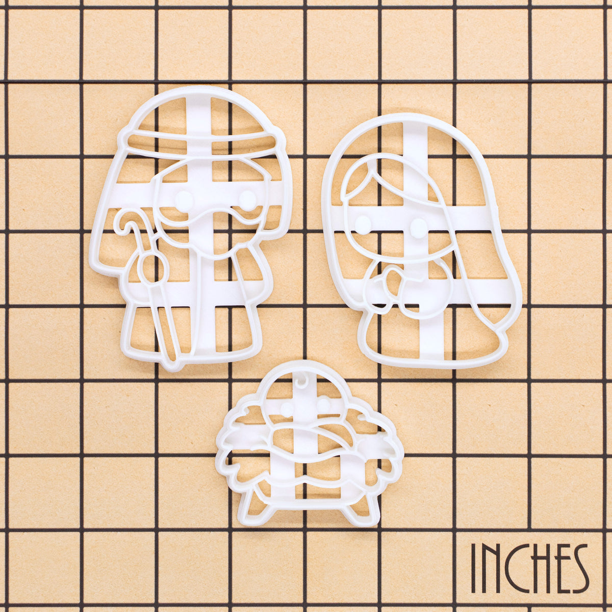 Set of 3 cute Nativity cookie cutters on a size grid in inches, featuring Mary, Joseph and baby Jesus in a manger for Christmas baking