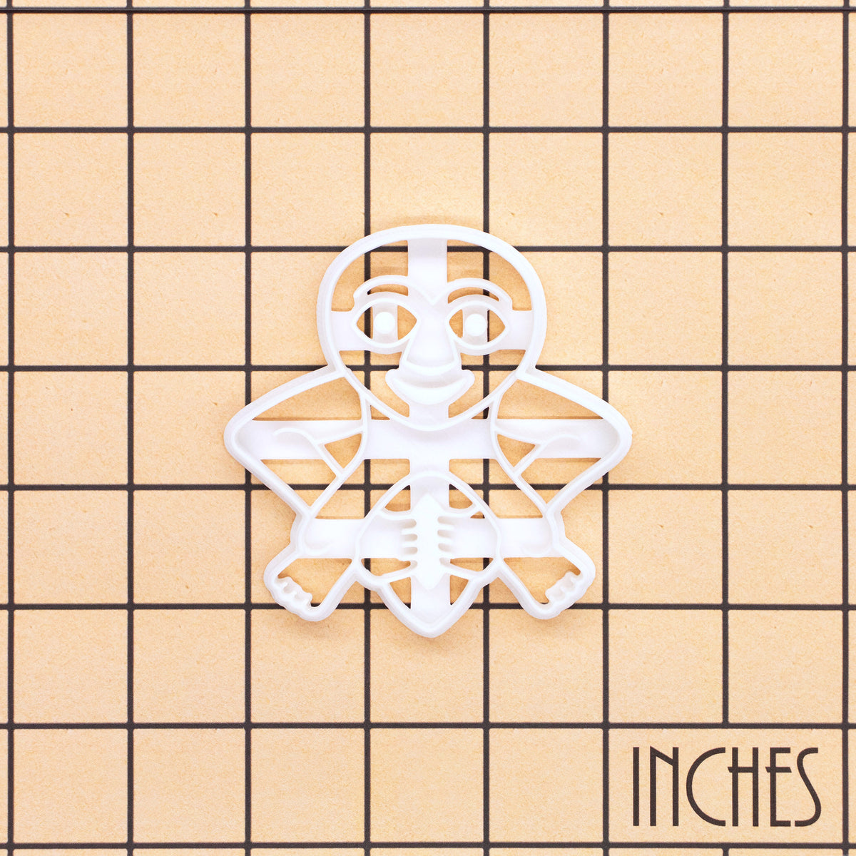 Sheela Na Gig figure cookie cutter shown on an inch measurement grid with detailed medieval figure design