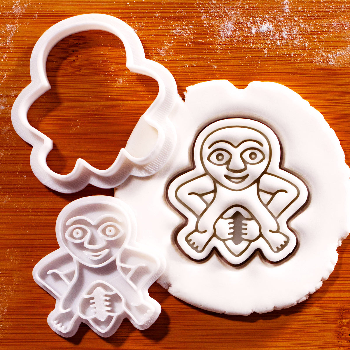 Sheela Na Gig mini 2-piece outline cookie cutter and detail stamp beside embossed white fondant