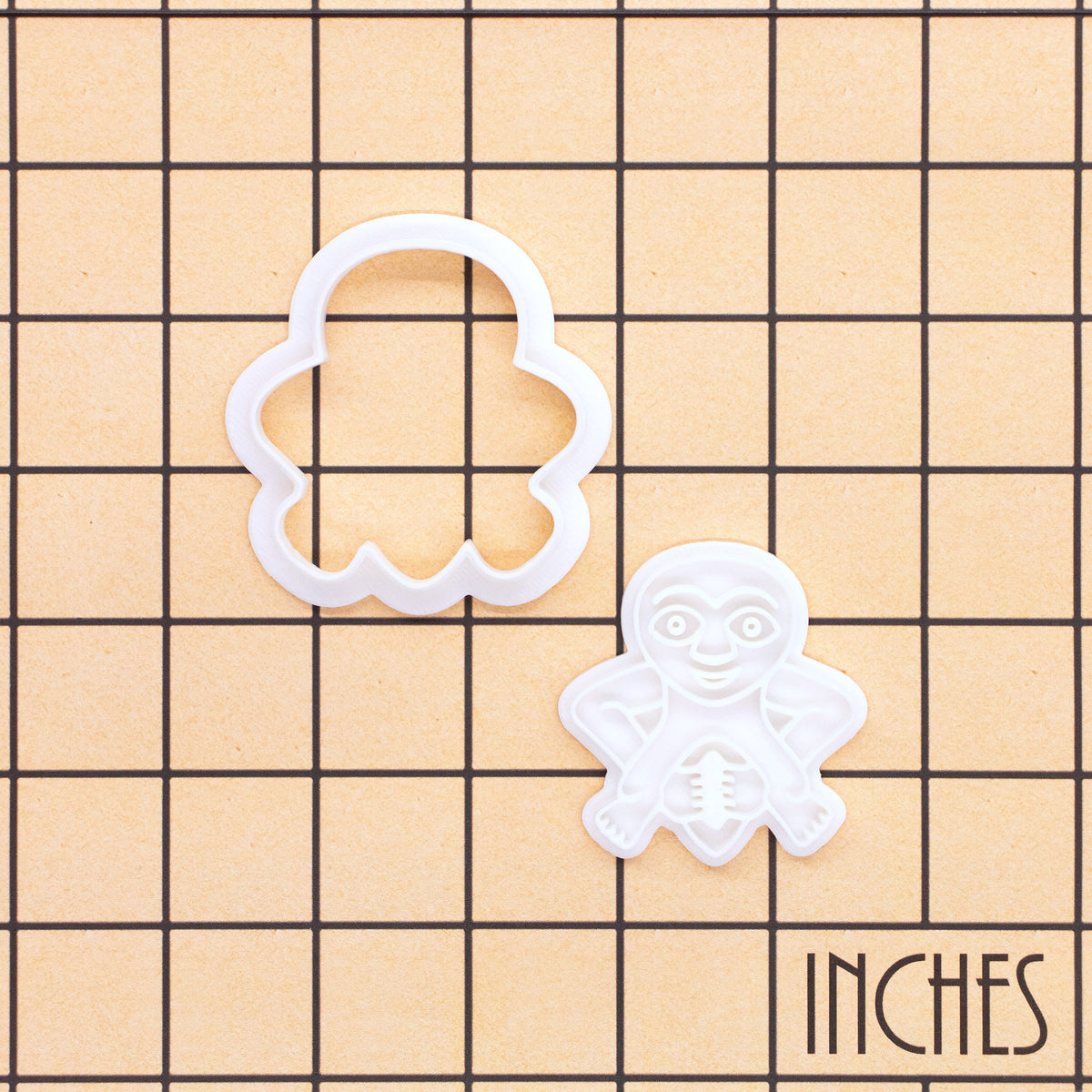 Sheela Na Gig mini cookie cutter and detailed stamp shown on an inch measurement grid