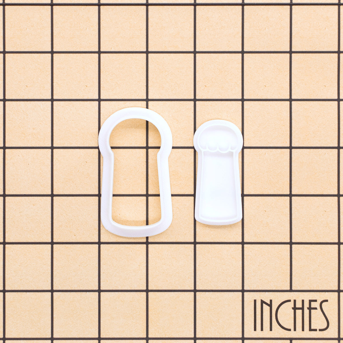 Lucky cat paw mini cookie cutter and stamp shown on an inch measurement grid