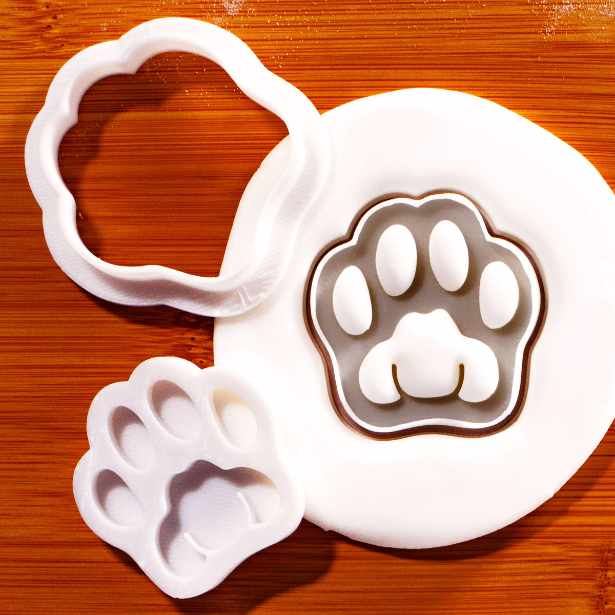Realistic kitty paw mini cookie cutter and separate paw stamp shown with detailed cat paw impression in fondant