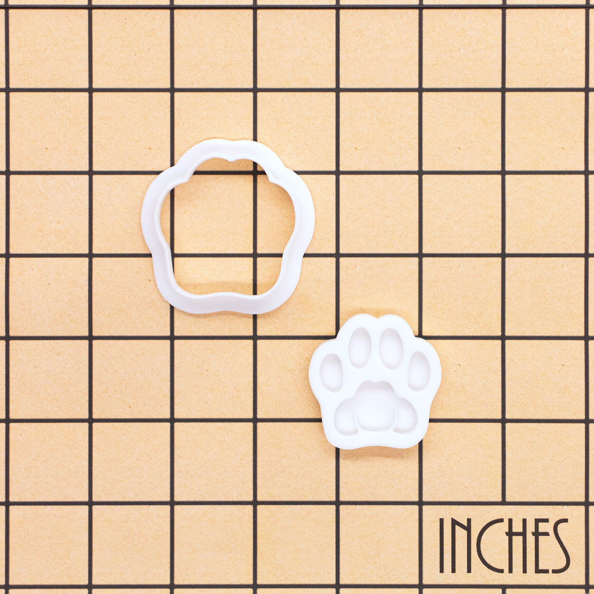 Realistic kitty paw mini cookie cutter and detailed stamp shown on inch measurement grid