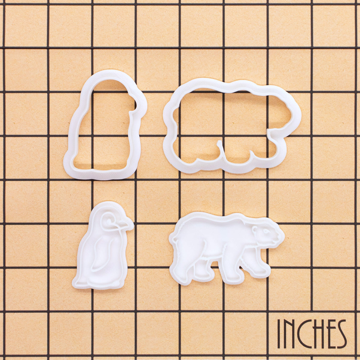 Polar bear and baby penguin mini cookie cutter and stamp set shown on inch measurement grid