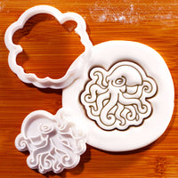 Realistic octopus mini cookie cutter and detailed tentacle stamp beside embossed sugarpaste octopus impression